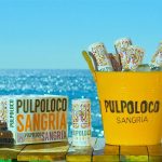 Image of a yellow bucket with pulpoloco sangria inside, over a wooden table with the beack on the back ground cartocan